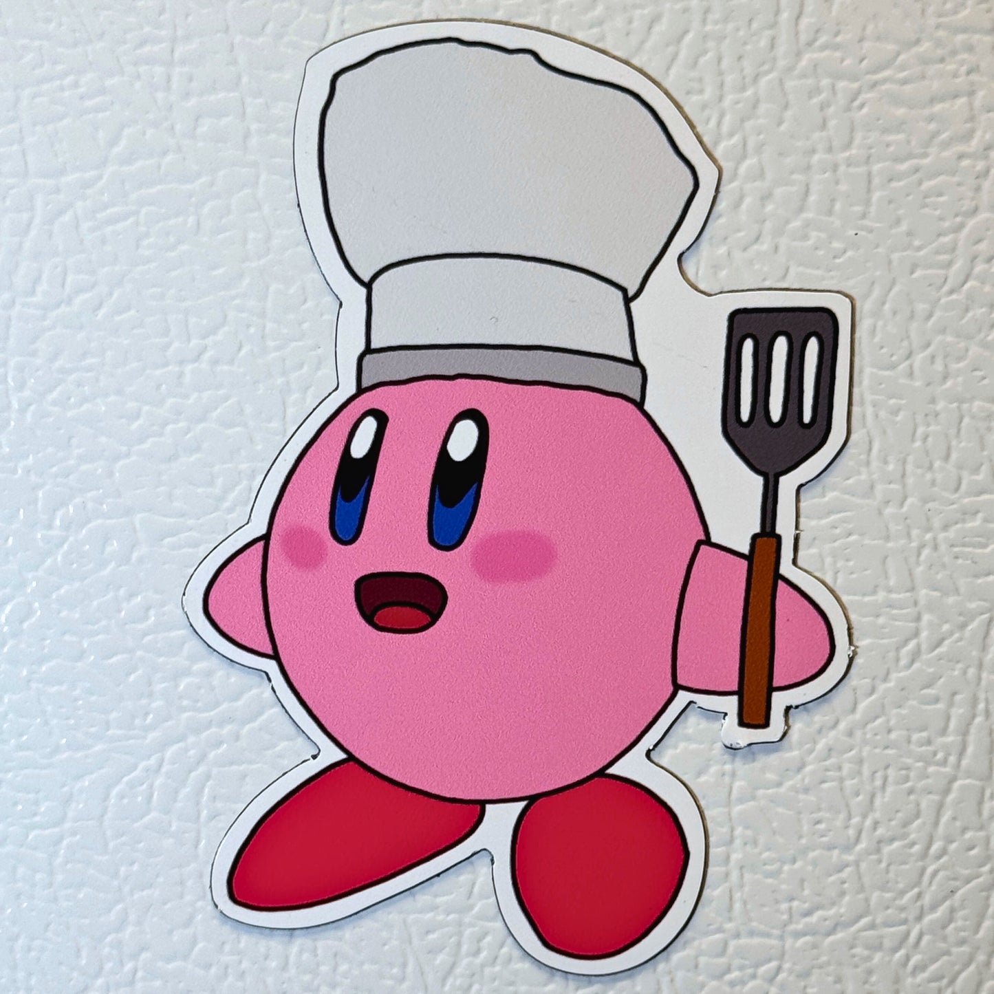 Kirby magnet with a chef's hat and spatula on a fridge