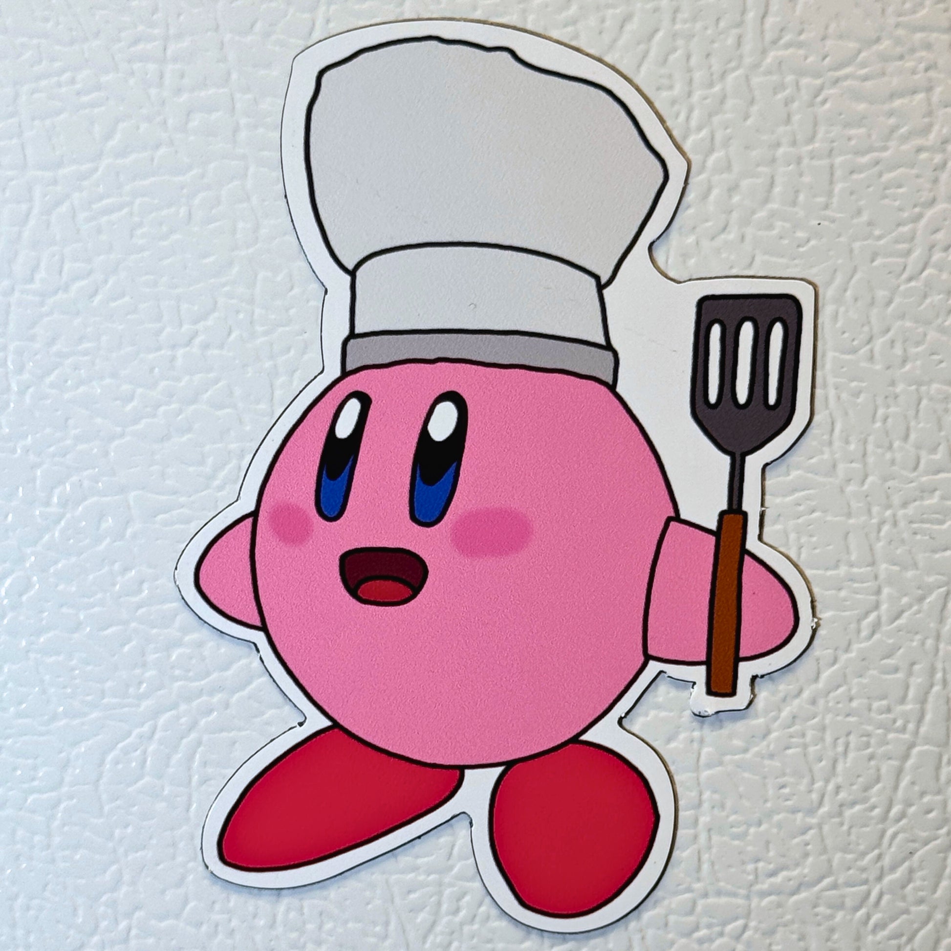 Kirby magnet with a chef's hat and spatula on a fridge