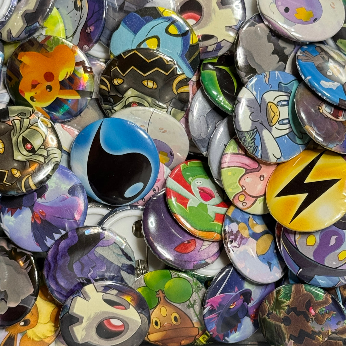 Pile of colorful upcycled Pokémon card buttons featuring assorted Pokémon characters and Energy symbols.